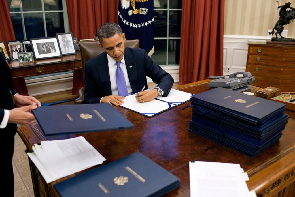 President Barack Obama signing papers in the whitehouse