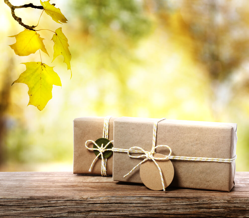 brown paper packages tied with string on a wooden surface and an autumn background