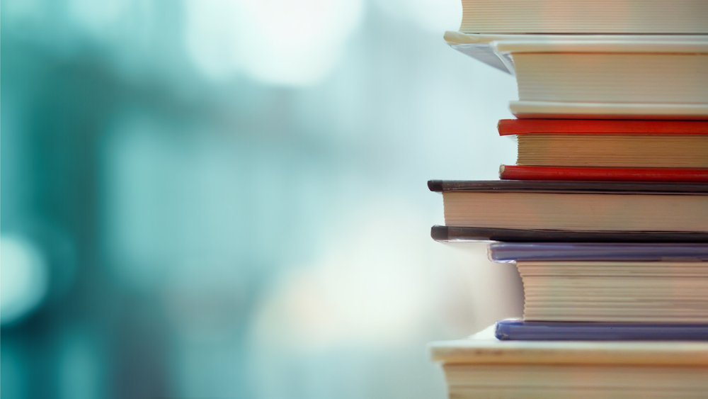 close up of a stack of books with an abstract blue background